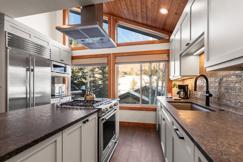 Modern alpine kitchen with scenic windows, vaulted ceiling, and premium appliances.