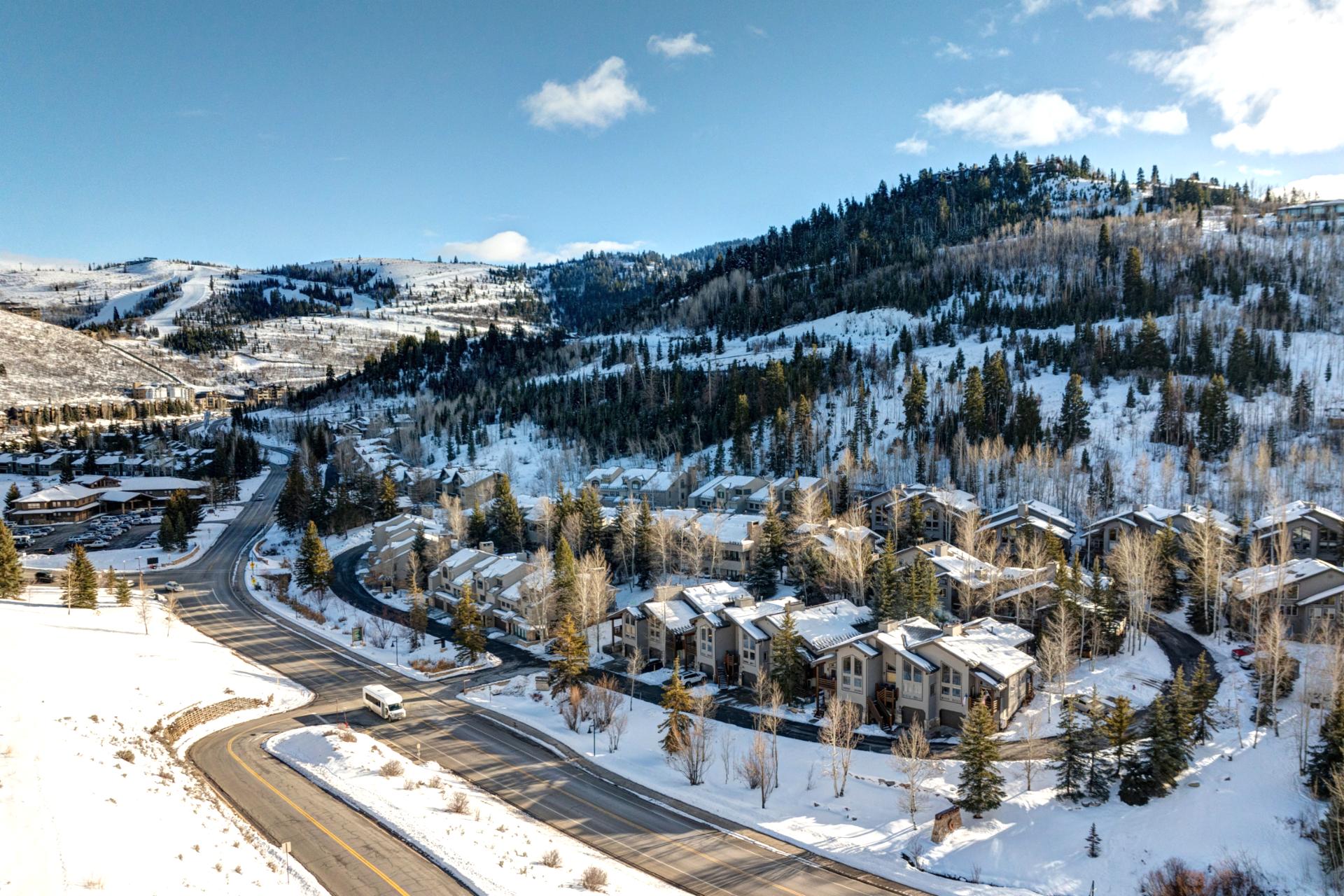 Peaceful winter setting with snow-covered hills, pine trees, and mountain views.