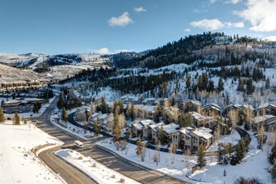 Peaceful winter setting with snow-covered hills, pine trees, and mountain views.
