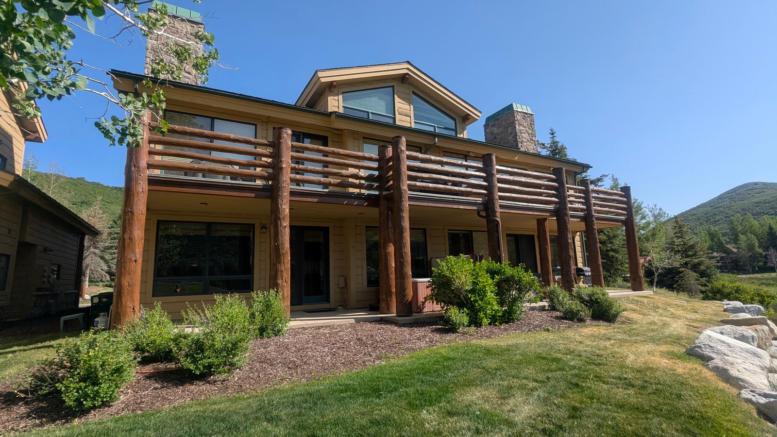 Private townhome exterior features two-story layout and wraparound deck with hot tub and BBQ.