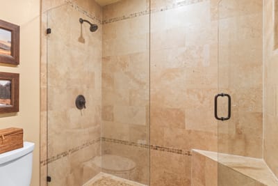 Walk-in shower with glass enclosure and natural stone accents elevates your primary bath experience.