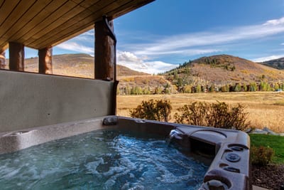 Step into your steamy spa with meadow views, set beneath a covered roof for all-season soaking.