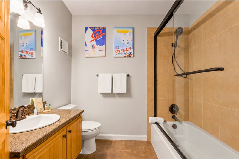 Guest bathroom with tub/shower combo styled with vintage ski-resort art