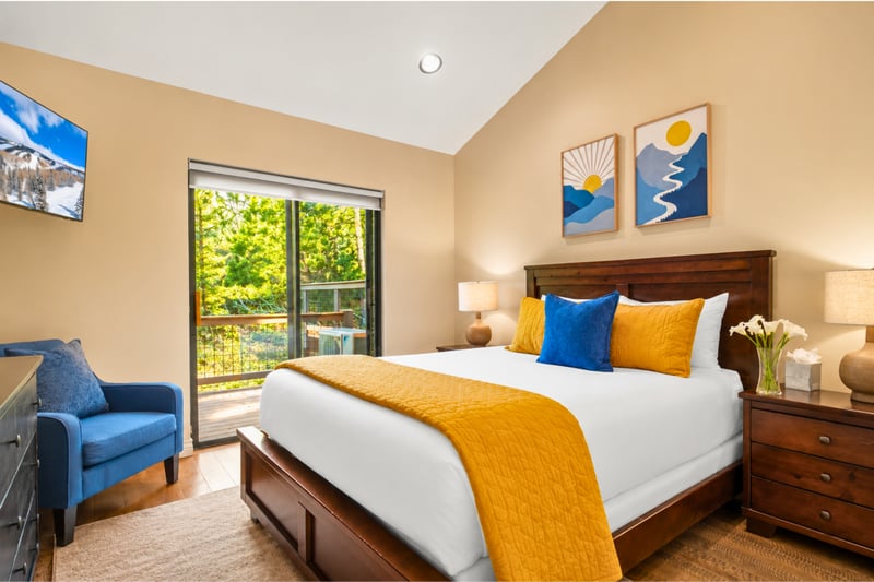 Spacious guestroom with a Queen bed and sitting chair, with private deck