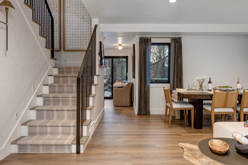 Entry staircase plaid stair runner leads up from the open dining and living space
