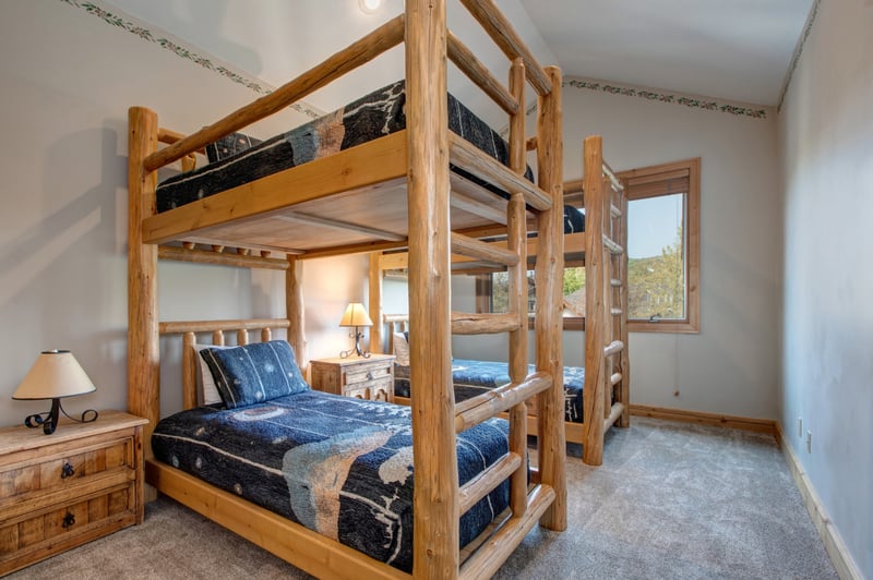 Wooden bunk beds and mountain-themed quilts create a fun, cabin-style retreat for younger travelers or friends sharing space.