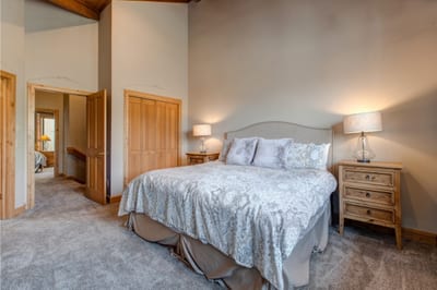 This King bedroom on the upper level offers plush bedding, soft lighting, and high ceilings. Perfect for quiet nights after mountain adventures.