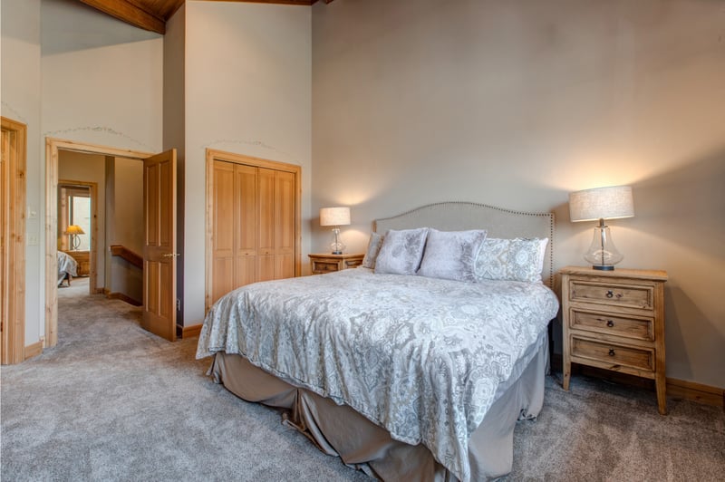 This King bedroom on the upper level offers plush bedding, soft lighting, and high ceilings. Perfect for quiet nights after mountain adventures.