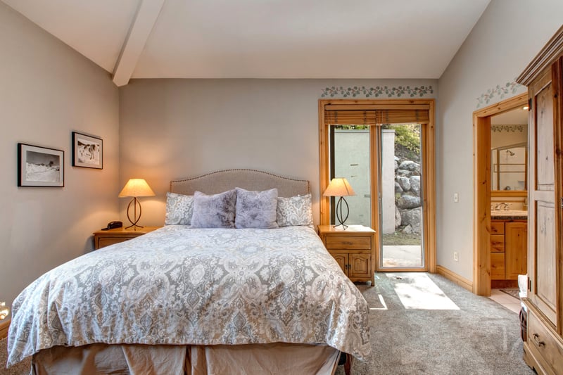 This main-level bedroom features a plush Queen bed, high ceilings, and private access to the outdoors, making it ideal for a quiet morning start or an evening retreat.