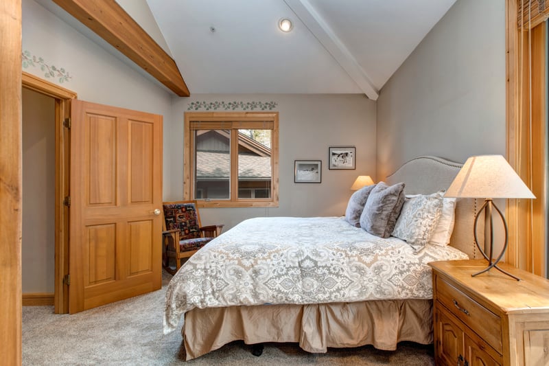 Located on the main level, this guest suite features a Queen bed, vaulted ceilings, and direct patio access with an ensuite bath just steps away.