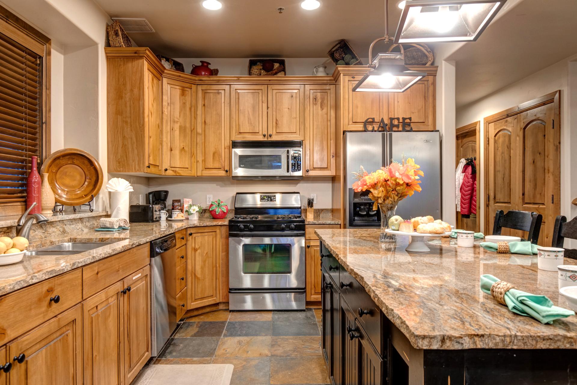 Rustic wood cabinetry and slate floors pair with stainless steel appliances for easy in-home cooking.