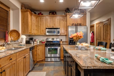 Rustic wood cabinetry and slate floors pair with stainless steel appliances for easy in-home cooking. PPS-1416