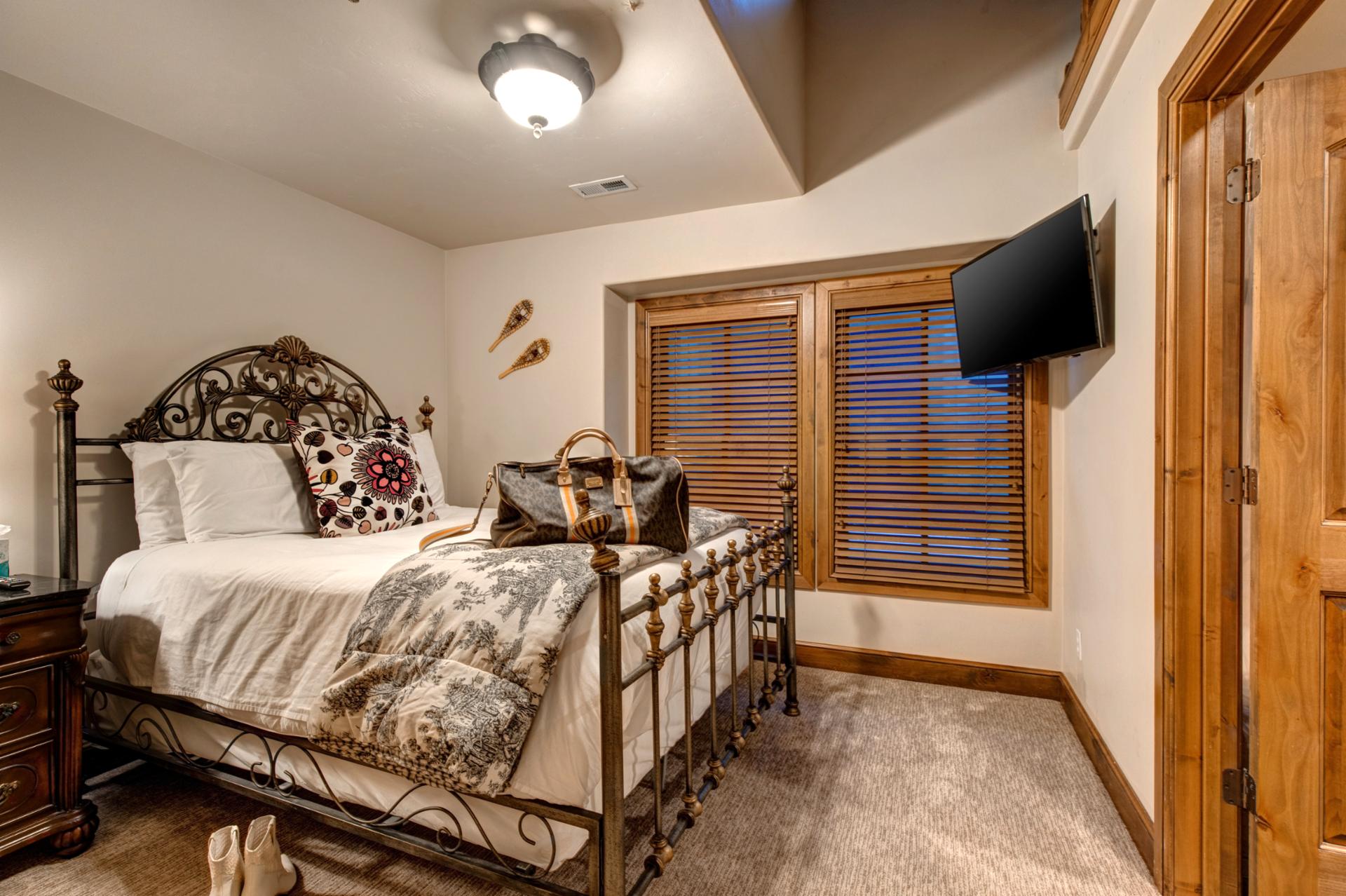 Elegant wrought iron bed pairs with warm wood furniture and soft lighting for cozy mountain charm.