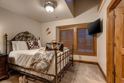 Elegant wrought iron bed pairs with warm wood furniture and soft lighting for cozy mountain charm.