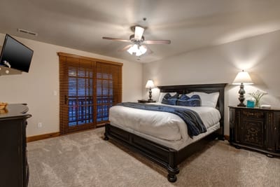 Spacious King bedroom with private balcony access, ceiling fan, and classic lodge-style furnishings. PPS-1416