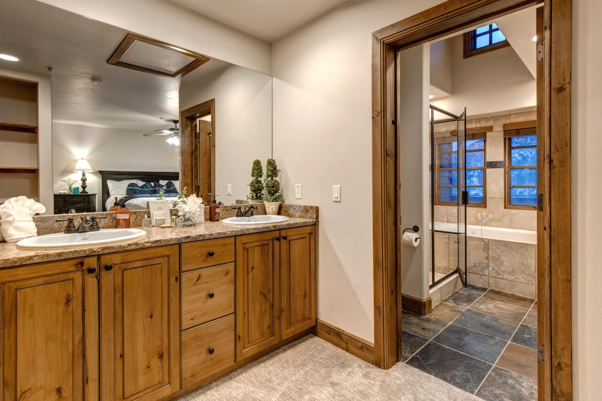 Double vanity, warm wood cabinetry, and soft lighting.