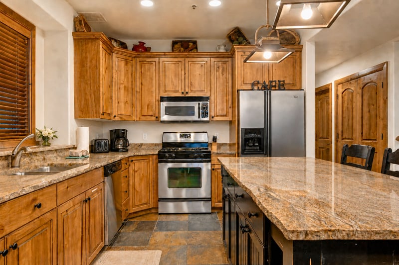 Rustic wood cabinetry and slate floors pair with stainless steel appliances for easy in-home cooking. PPS-1416