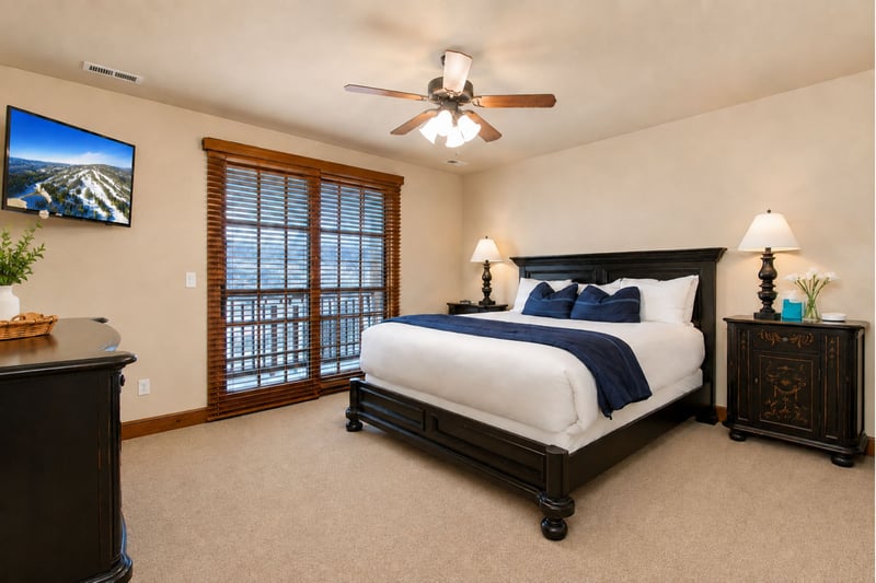 Spacious King bedroom with private balcony access, ceiling fan, and classic lodge-style furnishings. PPS-1416
