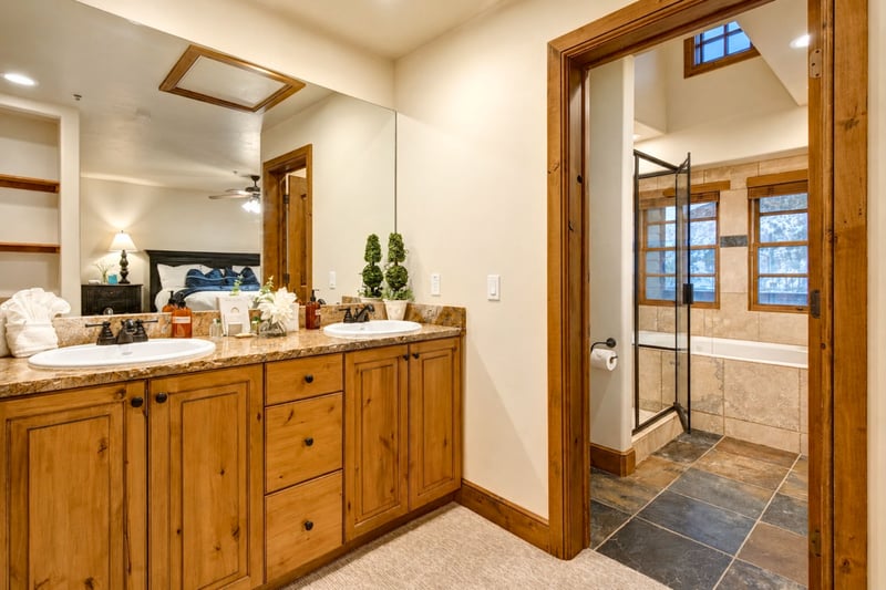 Double vanity, warm wood cabinetry, and soft lighting.