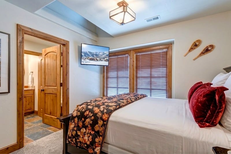 Guest bedroom with plush floral bedding, mounted TV, and an ensuite bathroom just steps away. PPS-1416