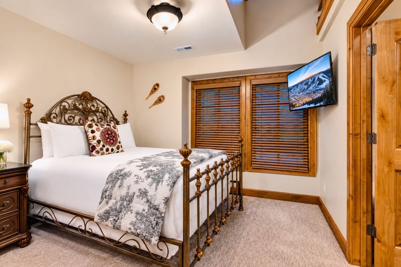Elegant wrought iron bed pairs with warm wood furniture and soft lighting for cozy mountain charm.