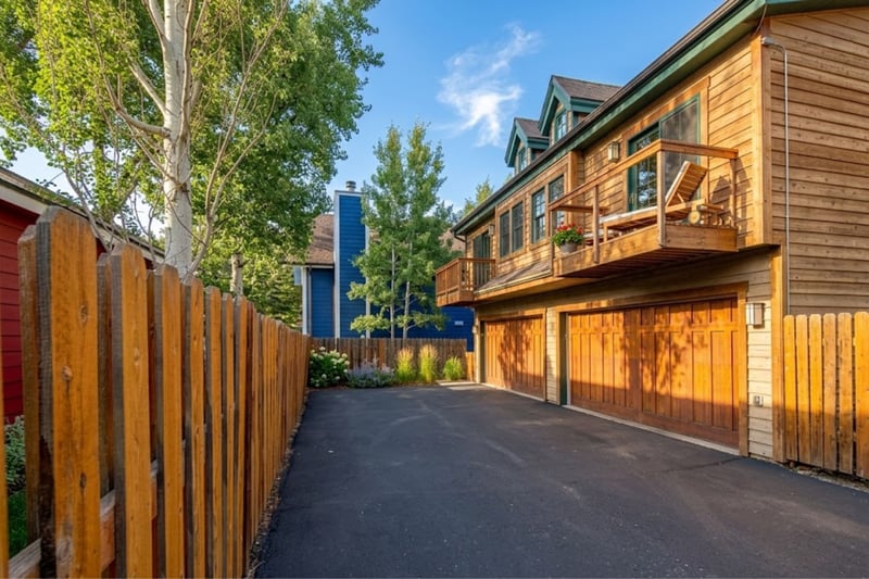 Private driveway leads to a rustic wood-paneled garage and two-level townhome with balconies. PPS-1416