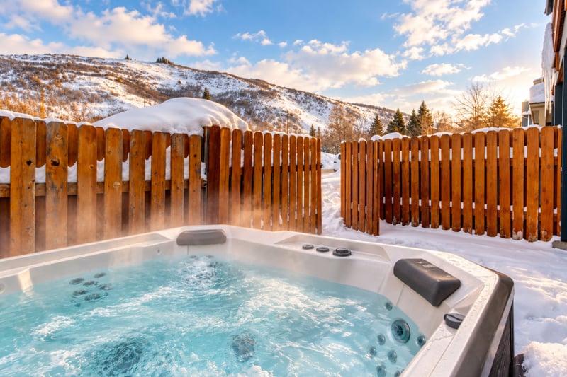 Soak in your private outdoor hot tub with scenic mountain views and peaceful privacy behind a wooden fence.