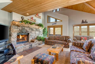 Vaulted ceilings and a wall of windows bring light and mountain views into the cozy living area.