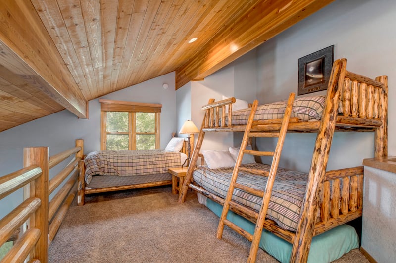 Guest Bedroom 5 is a cozy loft-style space with a Twin-over-Full bunk, separate Twin bed, and charming wood ceilings.