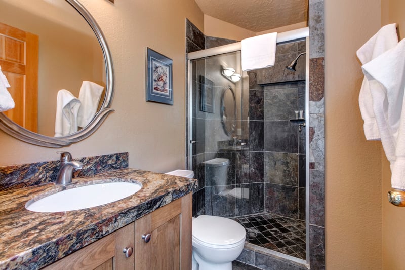 Guest Bath 1 includes a walk-in shower and stone accents with L’Occitane amenities provided.
