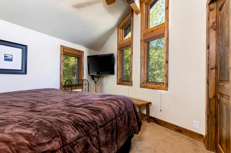Your upstairs primary suite includes a King bed, vaulted ceilings, and peaceful wooded views.