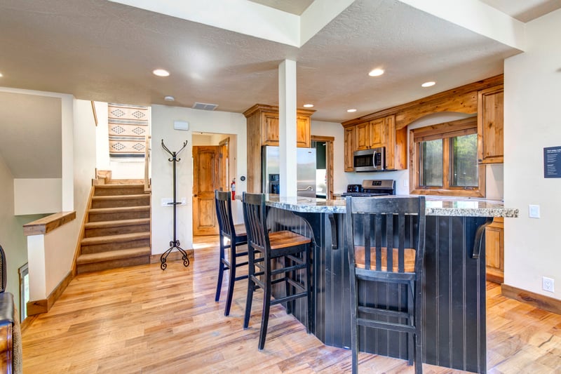 Open kitchen with breakfast bar, wooden flooring, and cozy living space.