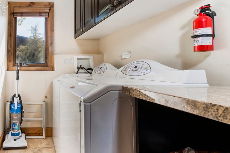 Laundry room with washer, dryer, vacuum, and spacious countertop surface.