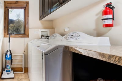 Laundry room with washer, dryer, vacuum, and spacious countertop surface.