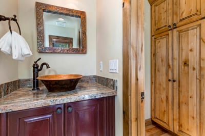 Elegant bathroom sink area with copper bowl and wooden cabinetry charm.
