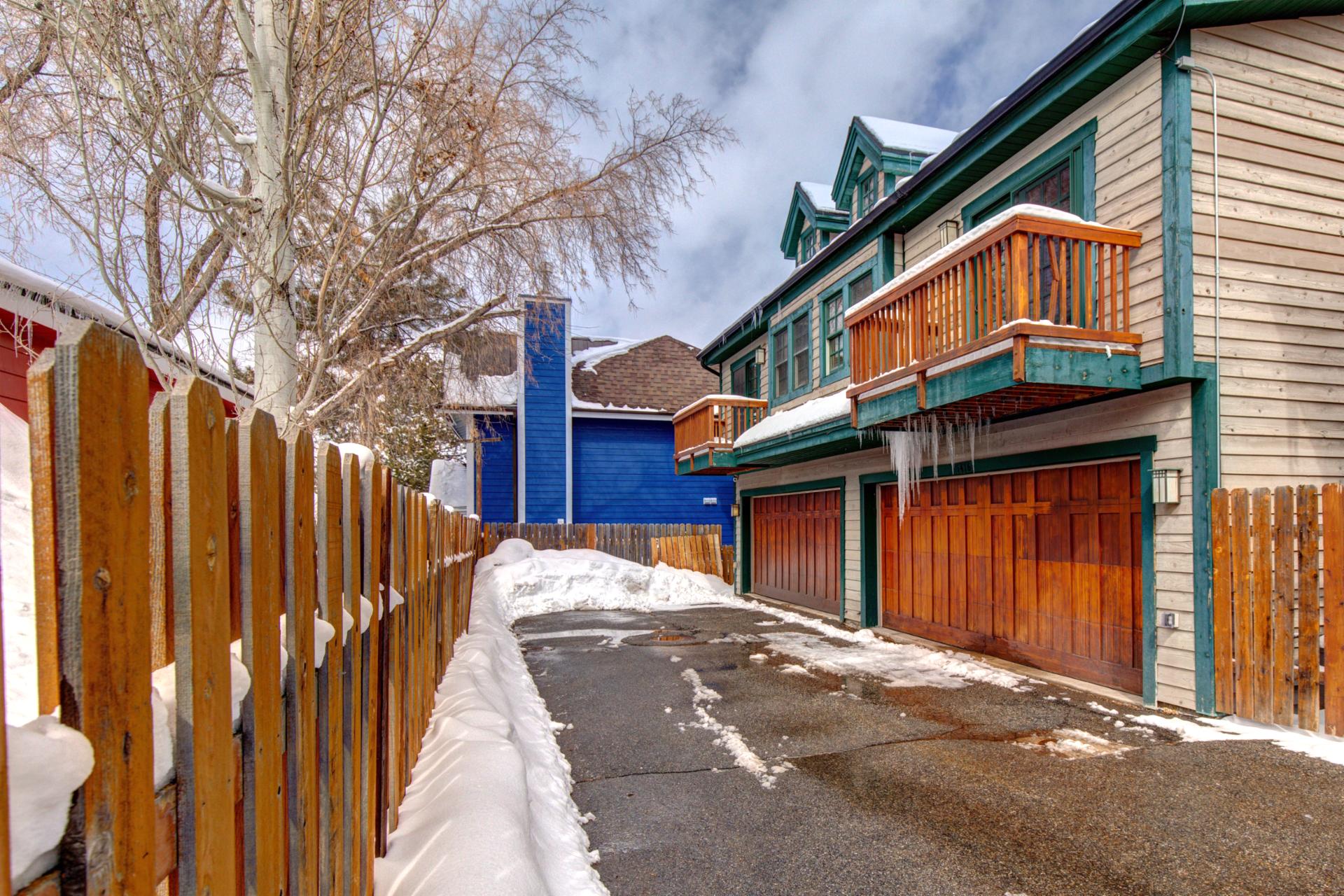 Private driveway leads to a rustic wood-paneled garage and two-level townhome with balconies.