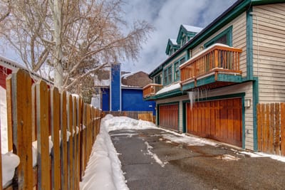 Private driveway leads to a rustic wood-paneled garage and two-level townhome with balconies. PPS-1416