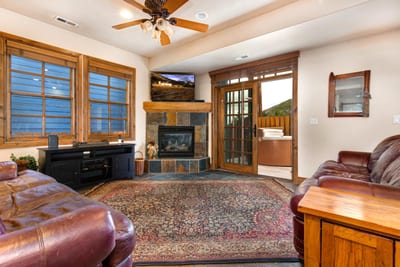 This cozy living room features a fireplace, large windows, and an open layout for easy gathering and game nights.