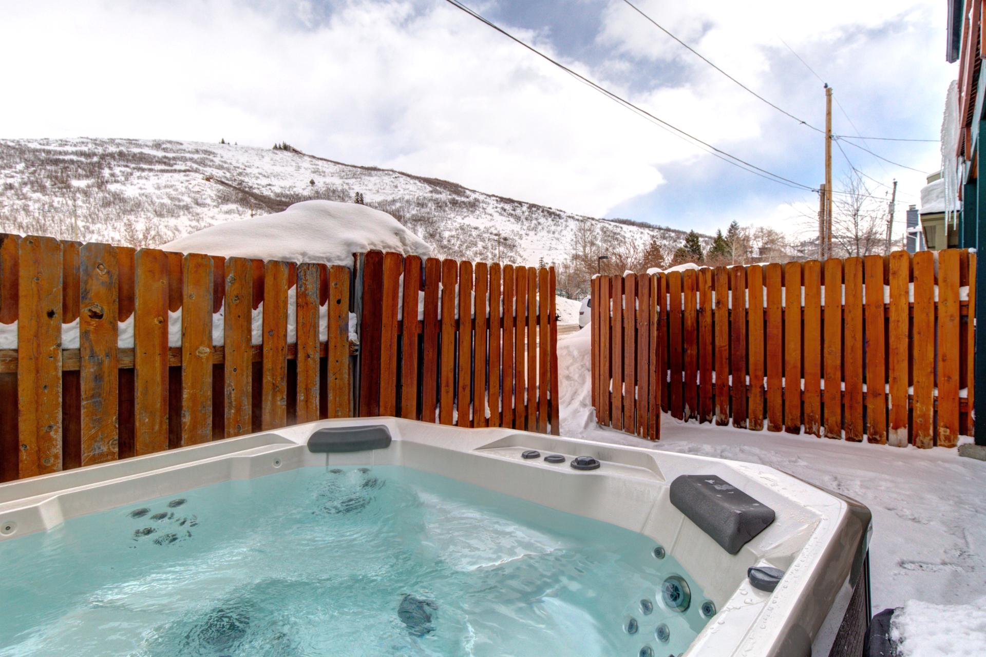 Soak in your private outdoor hot tub with scenic mountain views and peaceful privacy behind a wooden fence.
