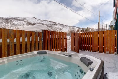 Soak in your private outdoor hot tub with scenic mountain views and peaceful privacy behind a wooden fence.