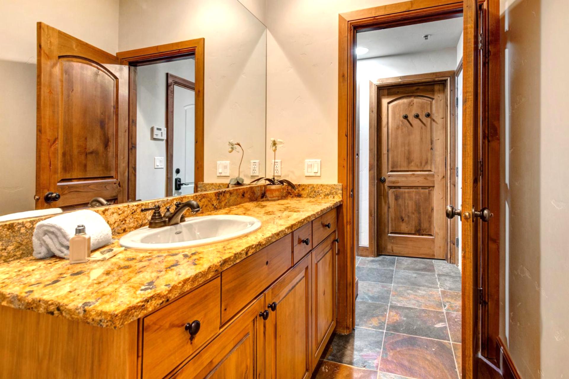 Guest bathroom with granite vanity, bright lighting, and a full shower-tub combo stocked with L’Occitane amenities.
