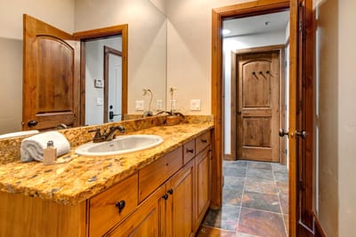 Guest bathroom with granite vanity, bright lighting, and a full shower-tub combo stocked with L’Occitane amenities.