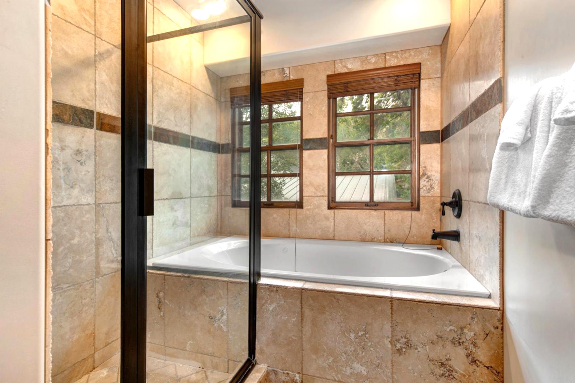 Large walk-in shower with stone tile and a window view makes for a relaxing start or end to your day.
