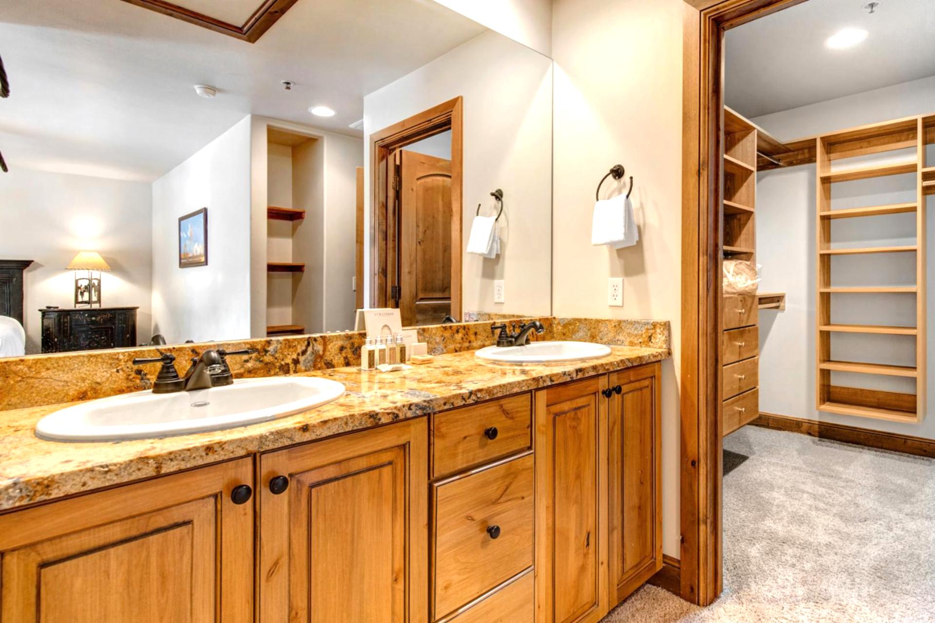 This spacious master bath includes a walk-in closet, dual vanities, and natural wood accents throughout.
