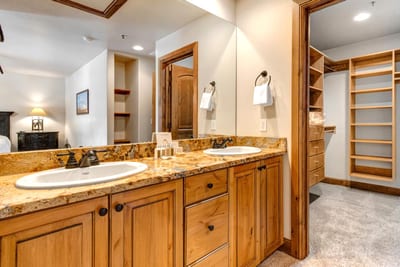 This spacious master bath includes a walk-in closet, dual vanities, and natural wood accents throughout.