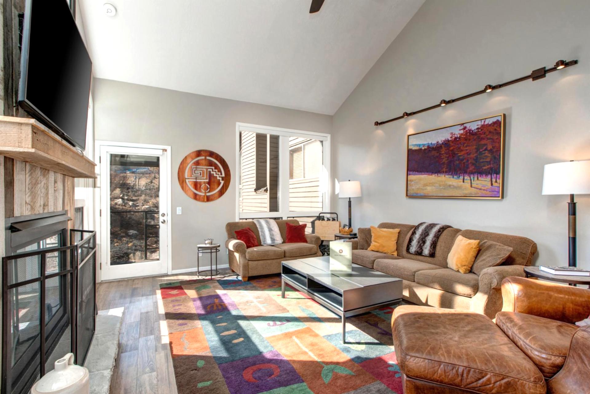 Vaulted ceilings and large windows fill the living room with light, with mountain views just beyond.