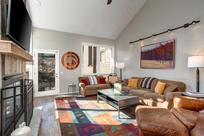 Vaulted ceilings and large windows fill the living room with light, with mountain views just beyond.
