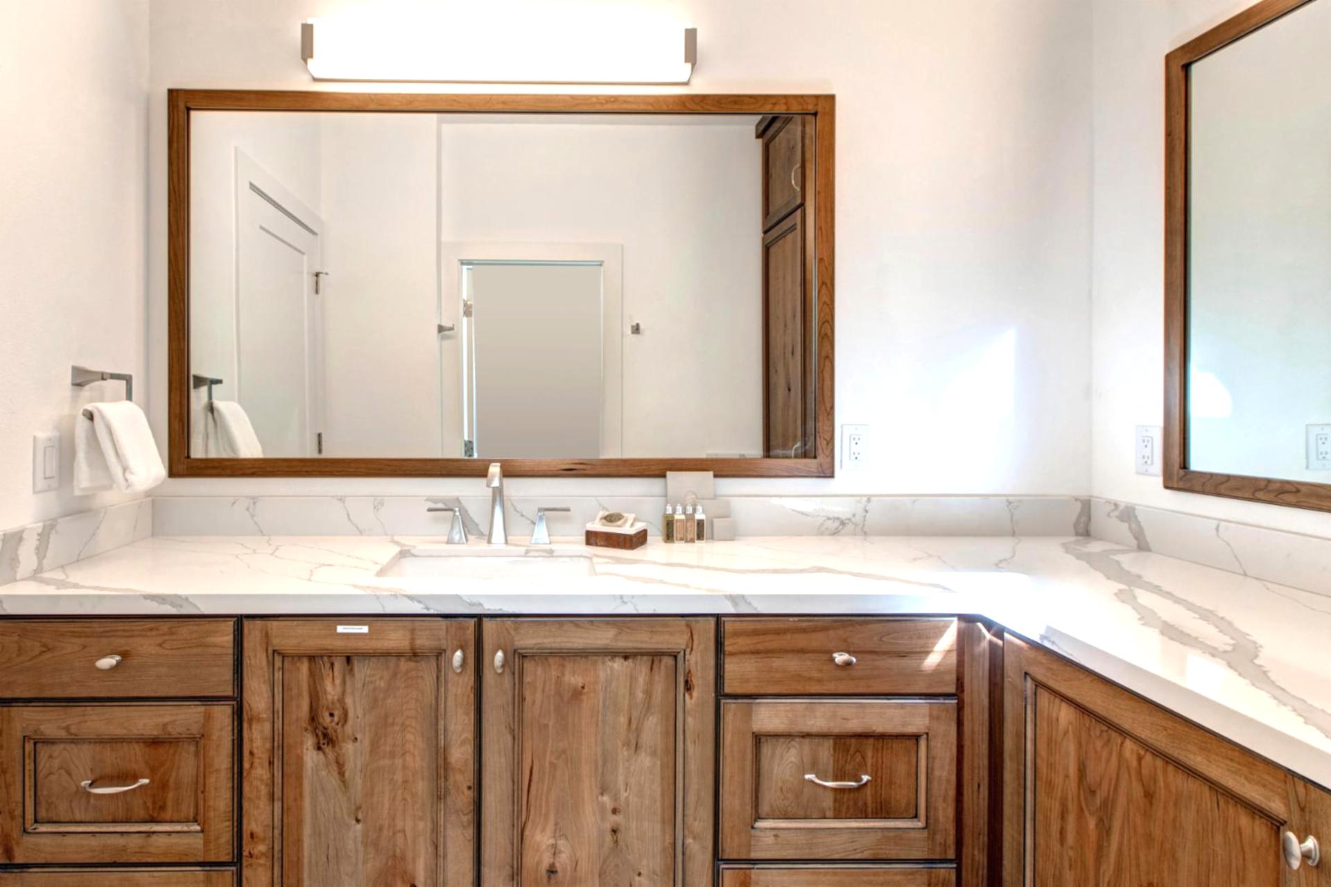 Another view of the spacious primary bath highlights warm wood cabinetry and natural light.