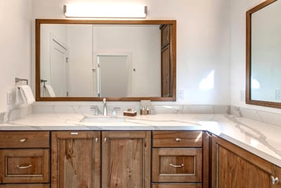 Another view of the spacious primary bath highlights warm wood cabinetry and natural light.