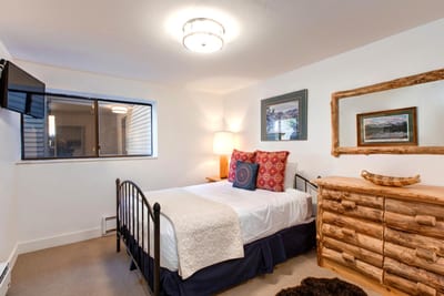 Main-level bunk room features a Full-over-Full log frame bed, cozy lighting, and mountain-inspired decor.